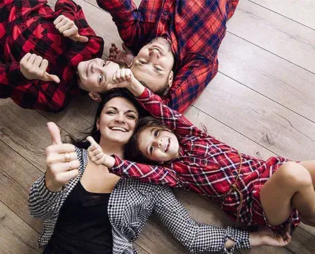 Happy family laying on hardwood floor | CR Carpet